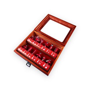 Twelve red router bits in an open wooden display case with a transparent lid pane and metal clasp